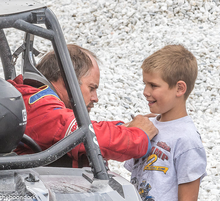 Racecar driver giving an autograph to a kid